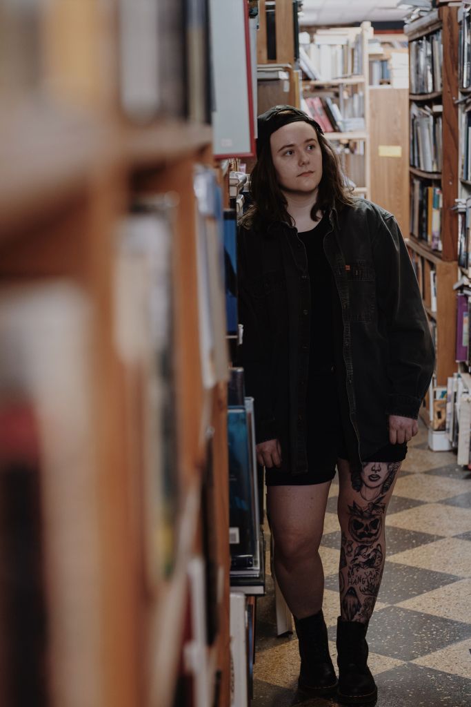 Ellie standing in a bookstore looking pensive.
